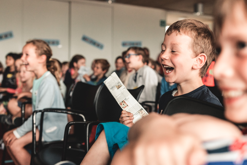 Lachende kinderen tijdens een auteurslezing in de bibliotheek